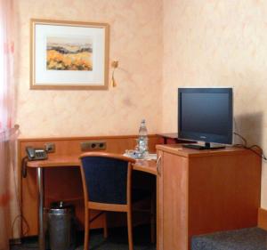 Zimmer mit einem Schreibtisch und einem TV darüber. in der Unterkunft Hotel Quellenhof in Bad Breisig