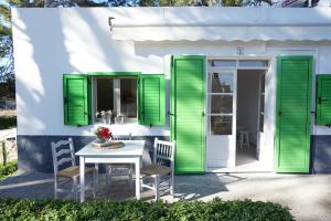 a white house with green shutters and a table and chairs at Bungalows del Lago - Astbury Formentera in La Savina