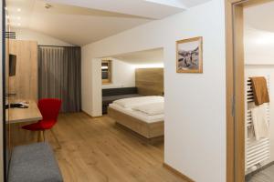 sypialnia z łóżkiem i czerwonym krzesłem w obiekcie Hotel Rosner w mieście Altenmarkt im Pongau