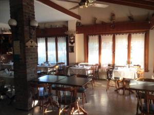 a dining room with tables and chairs and windows at Alpina Hostería in Villa Gesell