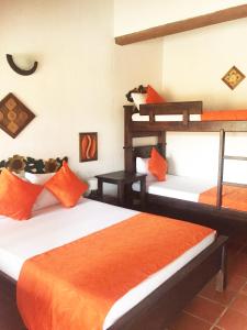 a bedroom with two bunk beds with orange sheets at Hotel Cristo Rey Campestre in Los Santos