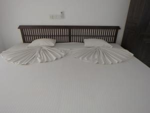 a large white bed with two pillows on it at Paradise Bay in Beruwala