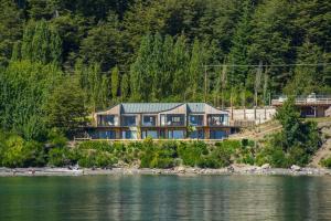 a house on the shore of a body of water at Correntoso TownHouses in Villa La Angostura