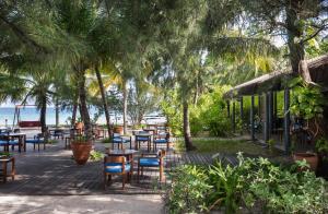 a patio with tables and chairs and the beach at Taj Coral Reef Resort & Spa - Premium All Inclusive with Free Transfers in North Male Atoll