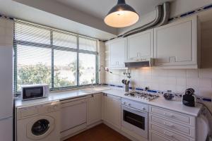 a kitchen with white cabinets and a washer and dryer at Moradia T3 Soltroia Mar in Troia