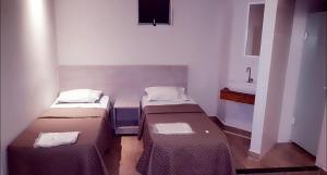 Habitación pequeña con 2 camas y lavamanos en Joy Hotel, en São Paulo