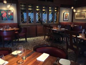 a restaurant with wooden tables and chairs and wine bottles at Inn By the Sea in Cape Elizabeth