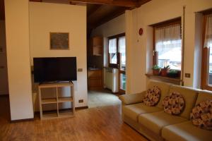 a living room with a couch and a flat screen tv at La Casa Duron in Campitello di Fassa