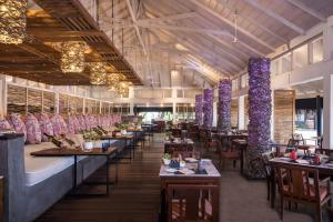un restaurante con mesas, sillas y columnas púrpuras en Taj Coral Reef Resort & Spa - Premium All Inclusive with Free Transfers, en Atolón de Malé Norte
