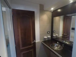 een badkamer met 2 wastafels en een houten deur bij Ayres del Bosque in Merlo +24 foto's