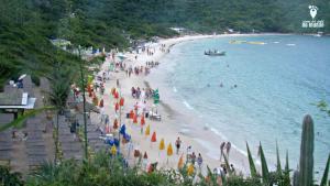 una multitud de personas en una playa cerca del agua en Linda Suíte perto da Praia do Forno, en Arraial do Cabo