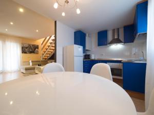a kitchen with blue cabinets and a white table and chairs at El Despertar in Boltaña