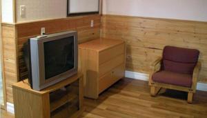 a living room with a tv and a chair at Dockside Motel in St. Barbe