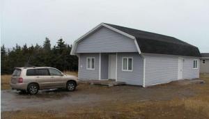 a car parked in front of a small house at Dockside Motel in St. Barbe