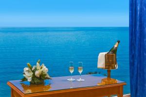 
a table topped with a glass of wine and a vase of flowers at Playadulce Hotel in Aguadulce
