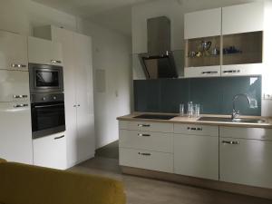 een keuken met witte kasten en een wastafel bij Stadtvilla Intzeplatz - Apartment Juist in Remscheid