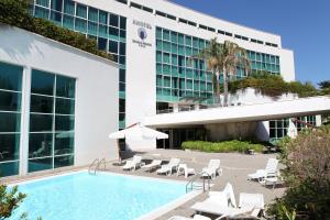 a hotel with a pool and chairs and a building at Nicotel Bisceglie in Bisceglie