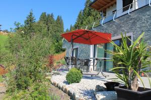 patio z czerwonym parasolem na domu w obiekcie Birnbacher-appartement w mieście Sankt Veit im Pongau