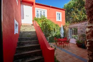 a staircase leading to a red house with a table and chairs at Sotam Country House in Góis