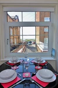 a table with glasses and plates and a window at The Coach House Apartment in Lytham St Annes