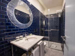 a blue tiled bathroom with a sink and a mirror at Apartamentos The Arc Carrís in Porto