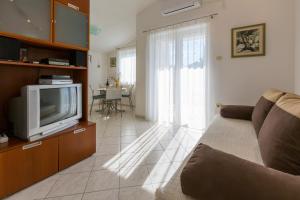 un salon avec un canapé et une télévision dans l'établissement Apartman Zrinko, à Dramalj