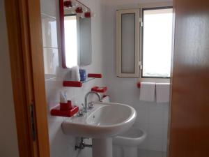 a white bathroom with a sink and a mirror at Hotel Coppa di Cielo in Peschici
