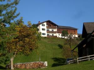 un bâtiment blanc au sommet d'une colline avec un arbre dans l'établissement Berghof Latzer, à Gurtis