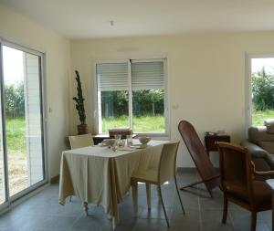 a dining room with a table and chairs and windows at La maison des fleurs in Saint-Senoch