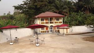 a building with tables and chairs and red umbrellas at Rose Garden Apartments in Limbe
