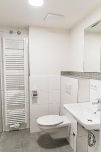 bagno bianco con servizi igienici e lavandino di Hotel Staffelseestraße a Monaco