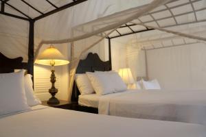 a bedroom with two white beds and a lamp at hotel florita in Jacmel +167 photos