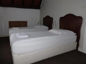 two twin beds in a room with white sheets at Bed and Breakfast Corvel in Tilburg