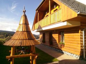 a wooden house with a wheel in front of it at Apartmány Lucie in Zdíkov