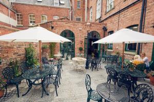 un patio al aire libre con mesas, sillas y sombrillas en The Old Coffee Tavern, en Warwick