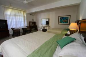 a hotel room with two beds and a television at Mima's Village Cozumel in Cozumel +86 photos