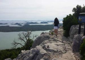 a woman standing on top of a mountain looking at the water at Apartmani kod Rade in Pakoštane