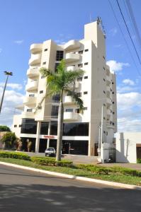 a white building with a palm tree in front of it at Colorado Plaza Hotel in Rio Verde