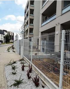 une clôture devant un bâtiment avec des plantes dans l'établissement Apartamenty Jesionowa, à Wrocław