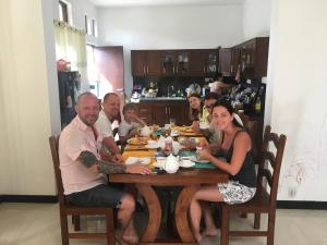a group of people sitting around a wooden table at Pick & Go White House in Negombo