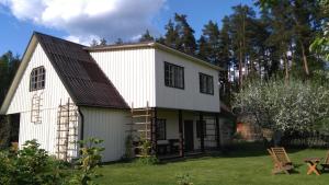 a white barn with a gambrel roof at Männi Farm Holiday House in Eoste