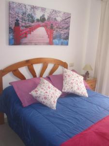 um quarto com uma cama com lençóis e almofadas azuis em Estudio Casco Los Silos, cerca de Garachico em Los Silos