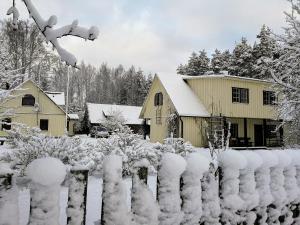 a fence covered in snow in front of a house at Männi Farm Holiday House in Eoste