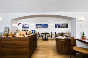 デュッセルドルフにあるホテル アム ホーフガルテンのカウンターとテーブルと椅子付きのレストランを併設しています。