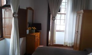 Un dormitorio con una cama y dos ventanas y una cómoda. en Casa Histórica San Sebastián, en Santa Cruz de la Palma