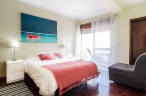 カスカイスにあるApartamento Costa Pintoのベッドルーム1室(ベッド1台、椅子、窓付)