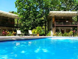 a swimming pool with two chairs and a building at Shakti in Santa Teresa Beach