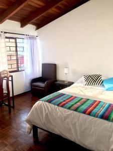 1 dormitorio con 1 cama, 1 silla y 1 ventana en Quito Kawsay, en Quito