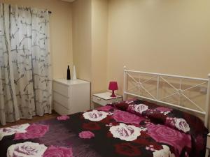 - une chambre avec un lit orné de fleurs roses dans l'établissement Apartamento Carvoeiro, à Armaes