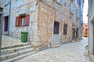 an alley with a trash can next to a stone building at Apartment Eleni in Rovinj